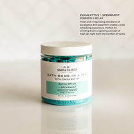 Aromatherapy bath bomb in a jar featuring the Eucalyptus + Spearmint blend. A refreshing mix of cool mint and invigorating eucalyptus for a spa-like self-care experience. Packaged in a clear jar with a minimalist label, highlighting its premium bath soak formula with cocoa butter for skin nourishment.