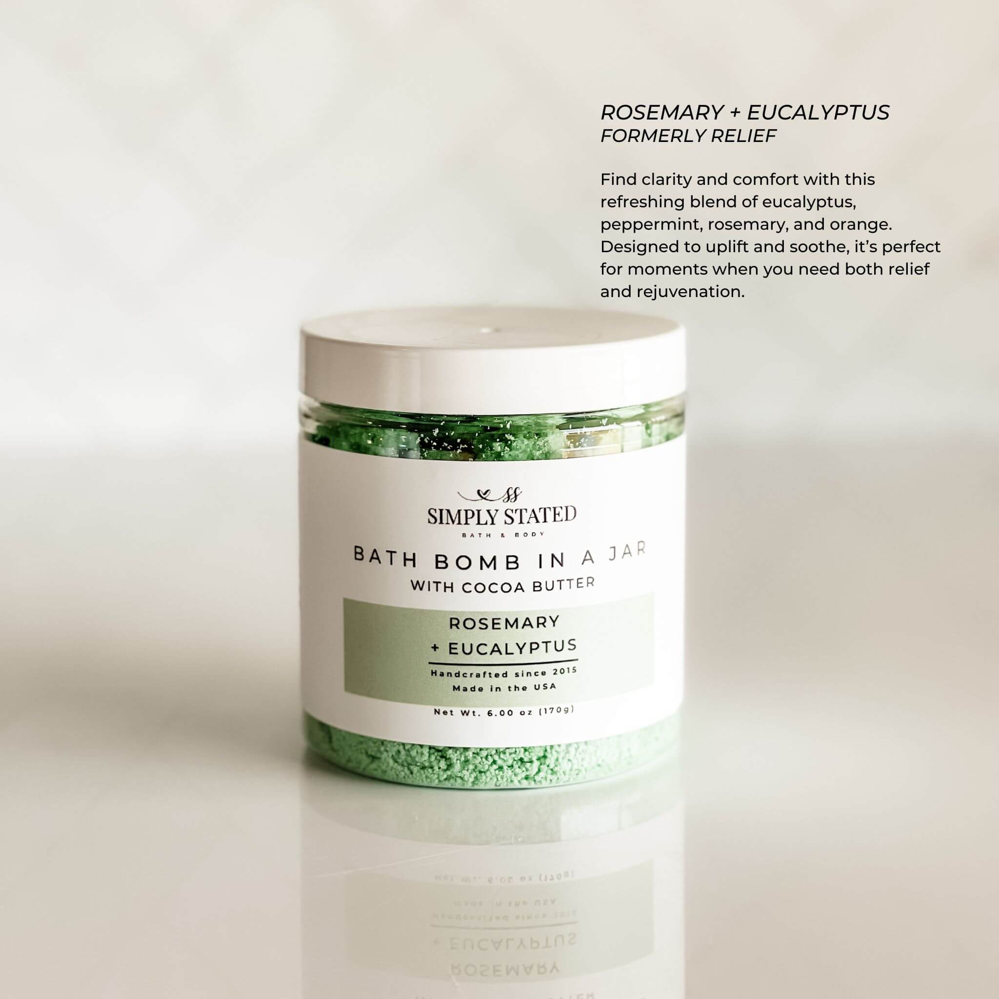 Aromatherapy bath bomb in a jar in the Rosemary + Eucalyptus scent. An uplifting blend designed to refresh and rejuvenate the senses, ideal for a stress-relieving soak. Packaged in a clear jar with a botanical-inspired green label, promoting relaxation and wellness.