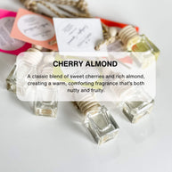 A set of car diffusers with clear glass jars and wooden lids, hanging from gold-colored chains.