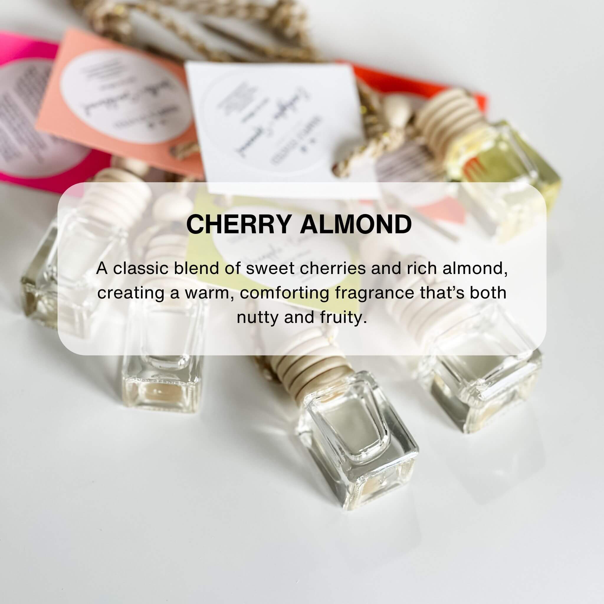 A set of car diffusers with clear glass jars and wooden lids, hanging from gold-colored chains.