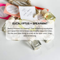 A set of car diffusers with clear glass jars and wooden lids, hanging from gold-colored chains.