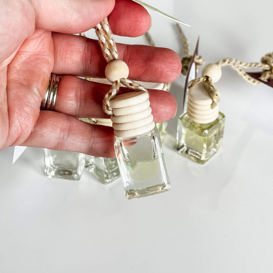 Close-up of hand holding Signature Car Diffuser bottle with wooden top