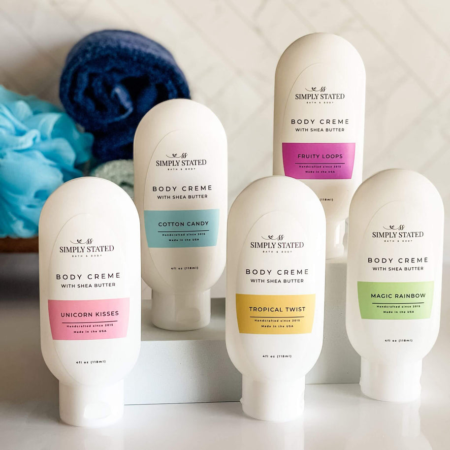 Collection of Simply Stated Body Creme bottles with colorful labels on a neutral background