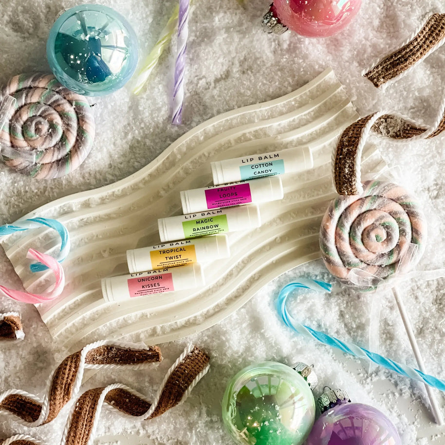 Set of lip balms on a decorative tray with candy-themed items.