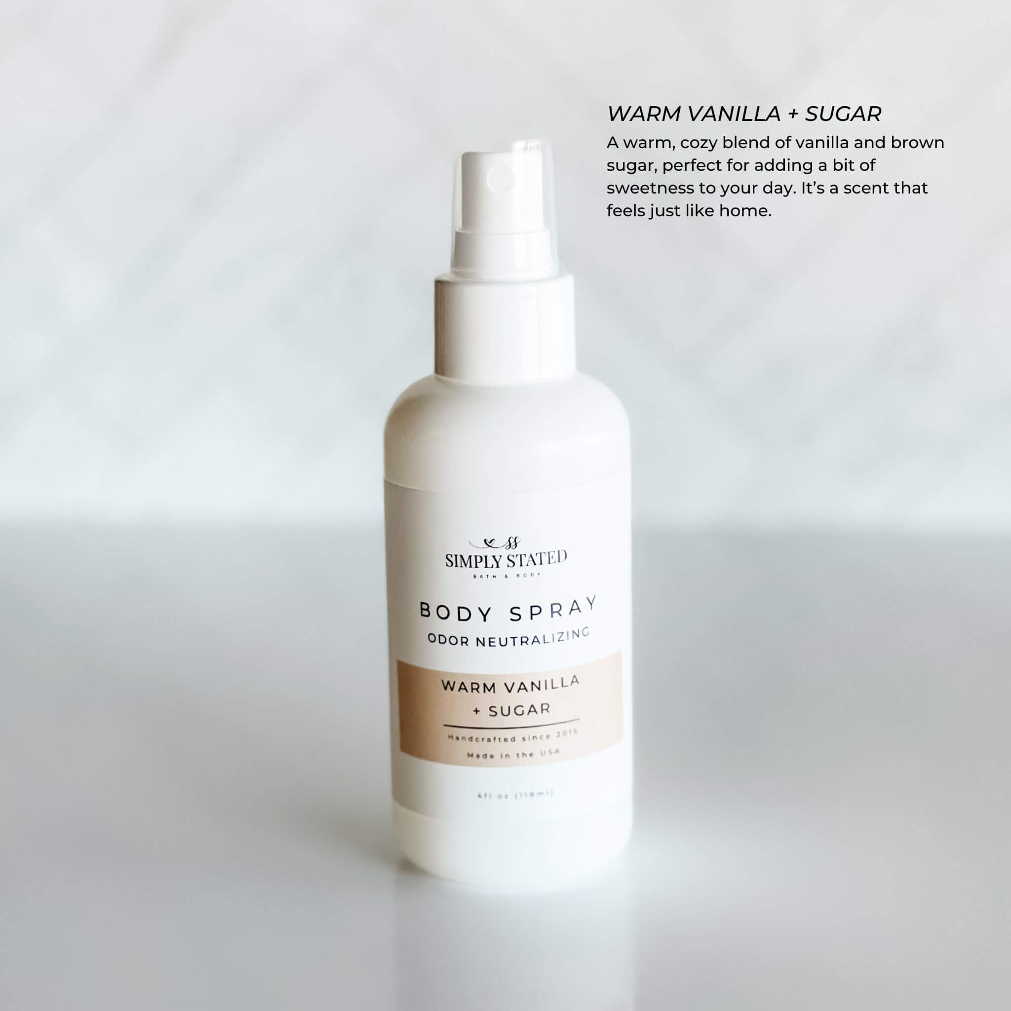 Simply Stated Warm Vanilla + Sugar Body Spray in a 4oz white bottle with odor-neutralizing formula. A cozy scent combining warm vanilla and brown sugar for a homey fragrance.